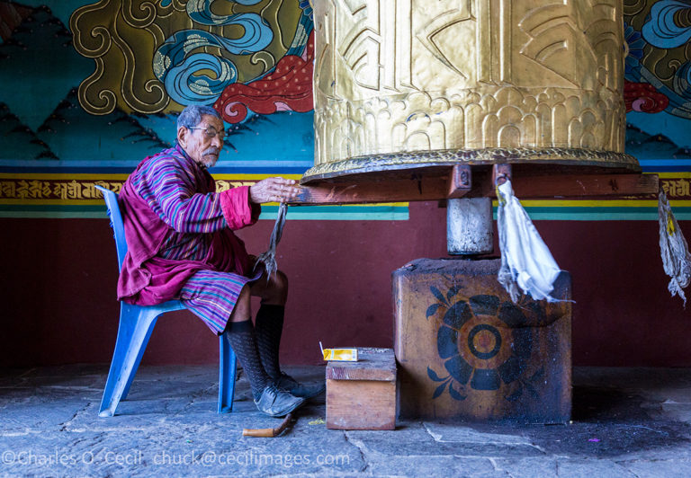 Punakha, Bhutan. Old Man Turning Prayer Wheel at the Punakha Dzong.