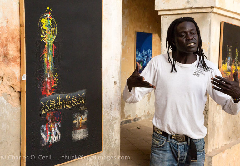 Artist "Mr. Co" (Corentin Faye) Explains his Painting, Biannual Arts Festival, Goree Island.
