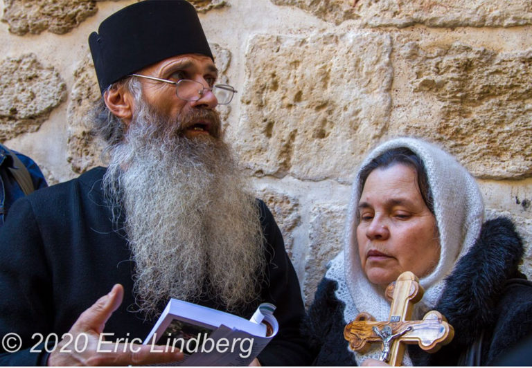 An Orthodox Christian priest and parishioner visit outside the main entrance to the Church of the Holy Sepulchre.