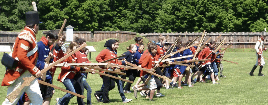 Youth "recruits" form a line and charge at Fort George