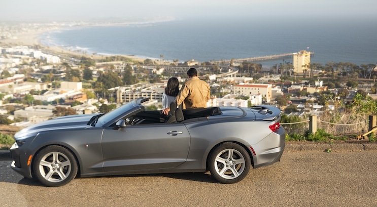 Couple looks out over Ventura and the California coast standing on a road