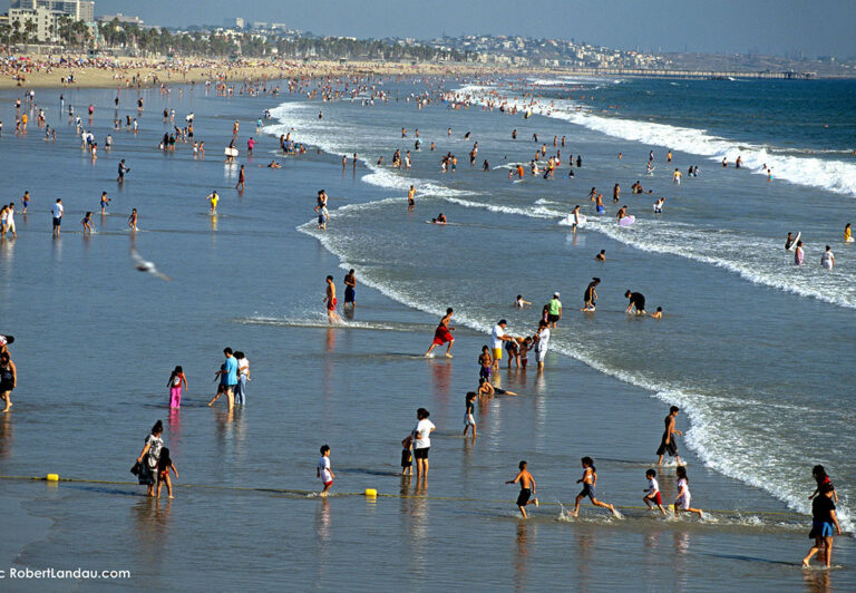 The view from the Santa Monica pier looking south shows an unbroken stretch of sandy beach that extends all the way to Venice Beach and beyond. Year round mild weather and the gentle surf at the shore provide a natural playground where locals and visitors alike come to relax and cool off.