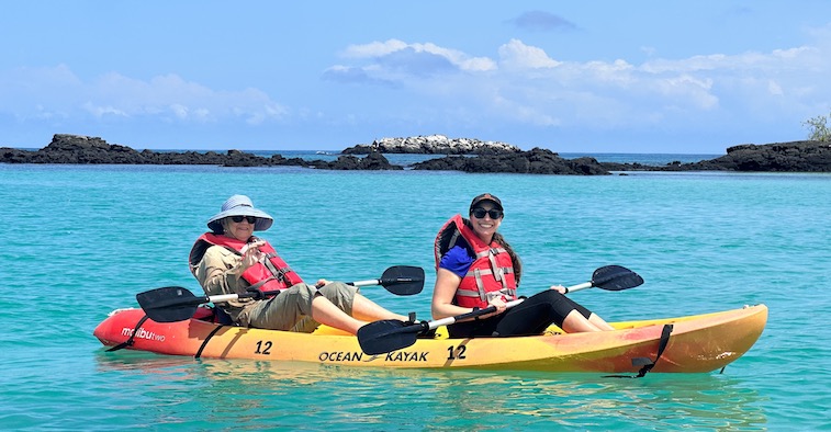 Two women paddling a sea kayak off the coast of Floreana Island.