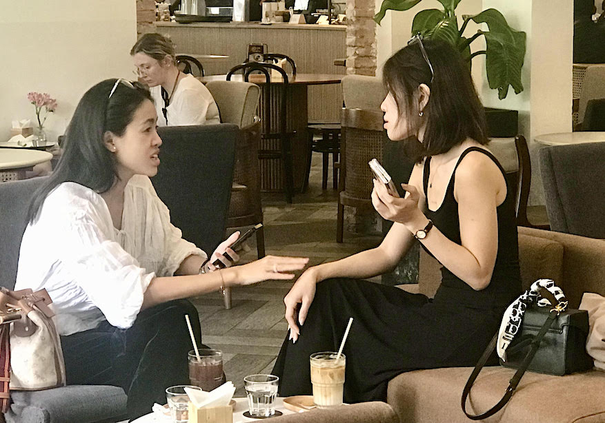 Two young women tell life stories while enjoying iced robusta coffee with sweetened condensed milk.