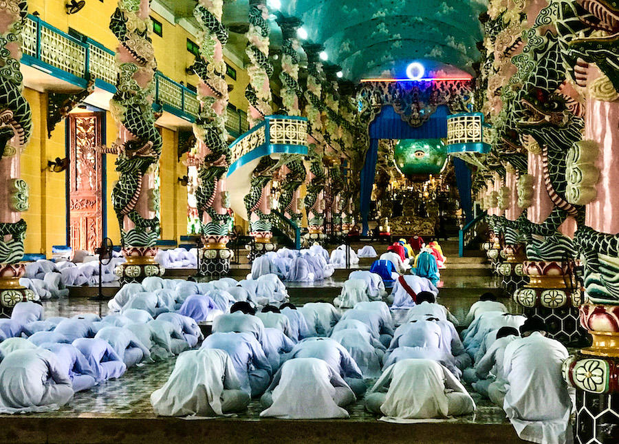 Cao Dai worshippers pray to the Goant Eye, which is set in a luminescent green and blue orb fashioned to resemble the earth.