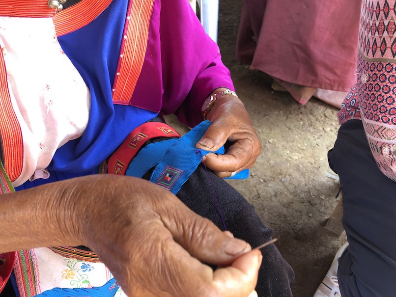 Lisu seamstress shows her work at Northern Thailand's Lisu Cultural Center. Photo by Nancy Wigston