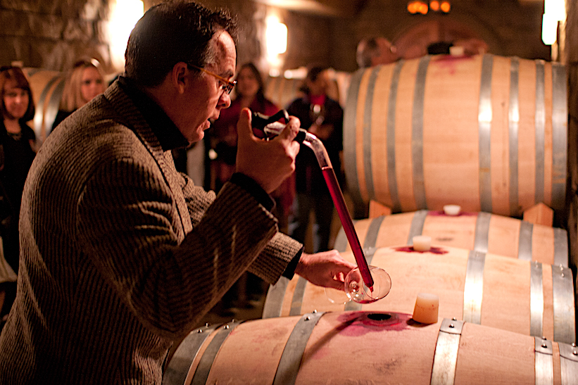 Stephen Reustle uses a "wine thief" to extract wine from a barrel in the cellar of his Prayer Rock Winery.