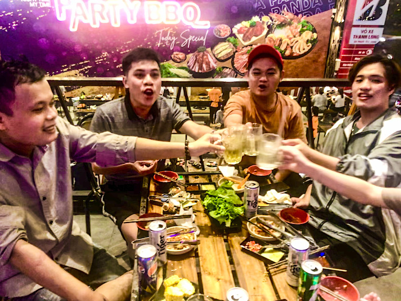 Young friends toast a celebratory evening at an open-air barbecue restaurant in Ho Chi Minh City.