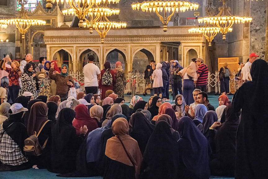 Young Muslim women plus a smattering of Western tourists listen to a guide inside the Hagia Sophia mosque in Istanbul.