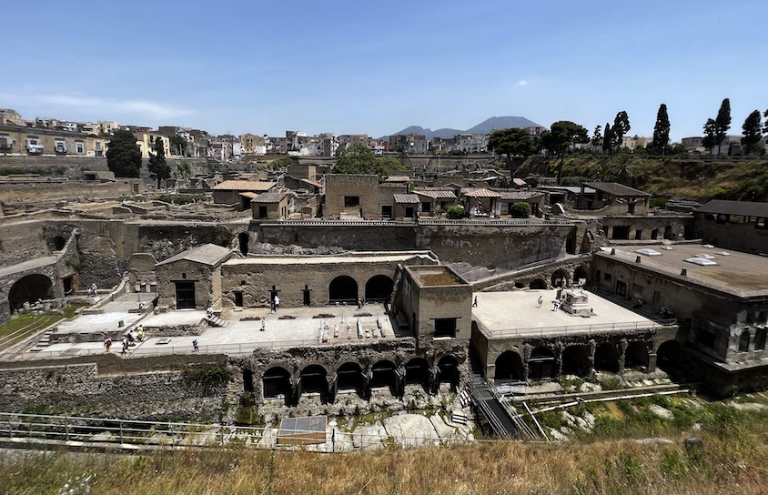 Only a fourth of Herculaneum, shown here with Mount Vesuvius in the background, has been excavated due to the fact that a modern town named Ercolano is built on top of it.