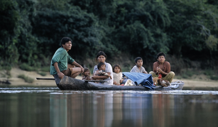 Indigenous family in a dugout canoe on the Essequibo River running through Guyana's Iwokrama Rainforest.