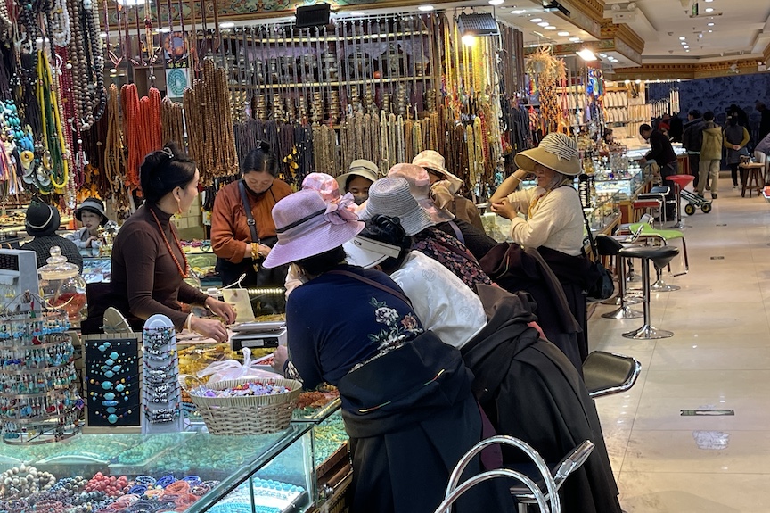 Shops around Lhasa's Barkhor Square sell a variety of fashion accessories. These shoppers are Tibetan women whose hats are designed to protect them from the intense sunshine.