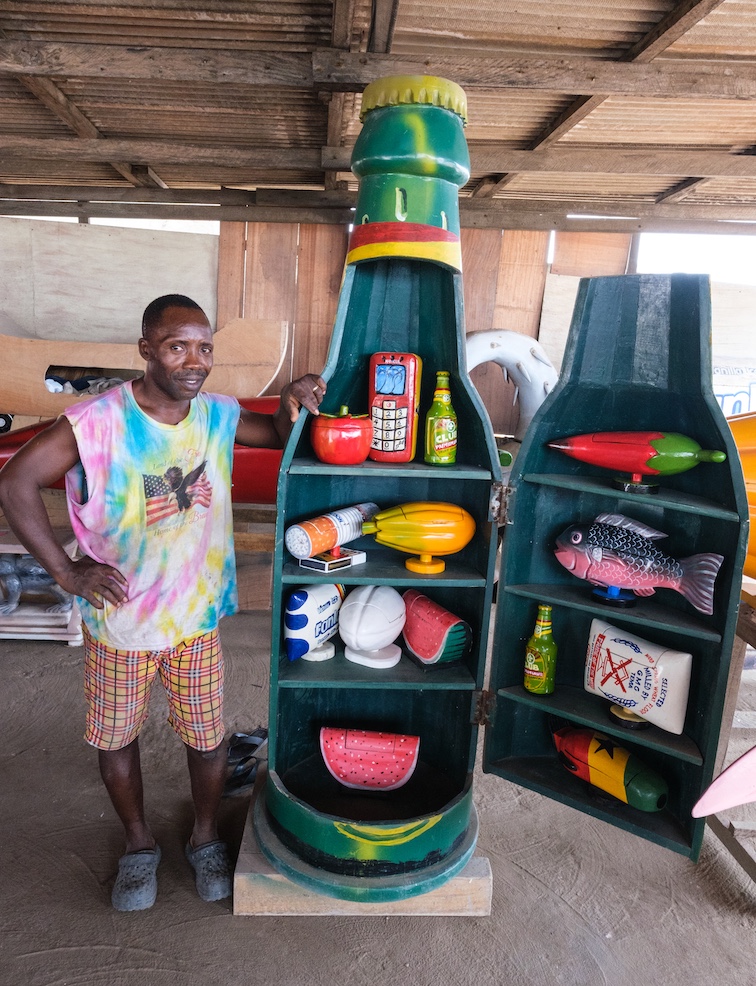 Accra Coffin maker Erick Kpakpo Adotey with a casket in the shape of a Beer Bottle. Shelves inside can be used for the storage of household items until the need for burial arises.