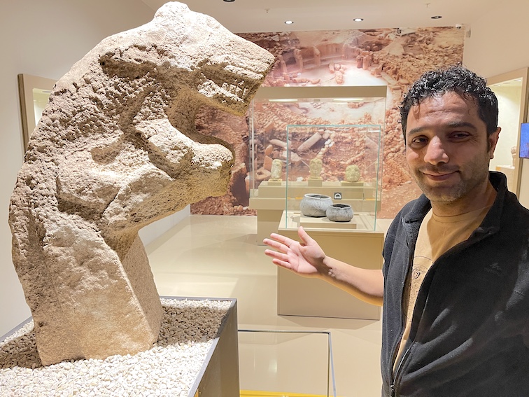 Archaeologist Ahmet Yavuzkir beside neolithis statue of a wild boar.