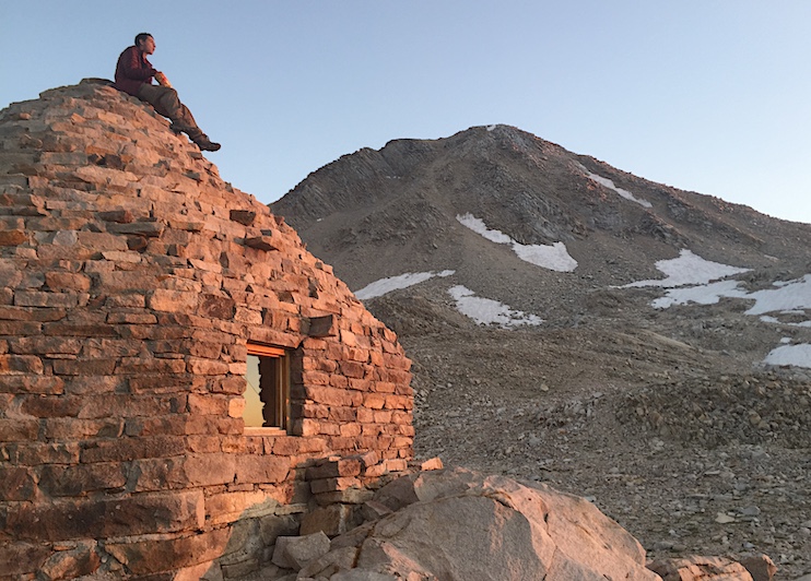 A hiker contemplates Mount Solomons from the top of the Muir Hut. 