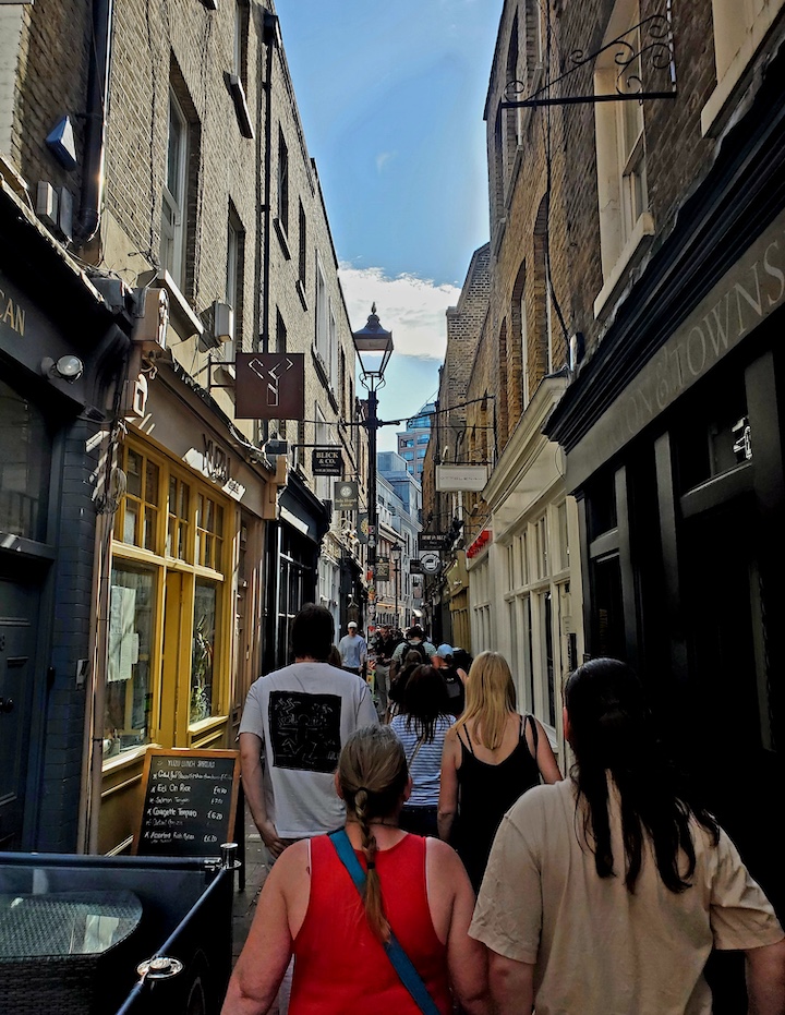 Tourists on a Jack the Ripper tour walk down a Whitechapel lane.
