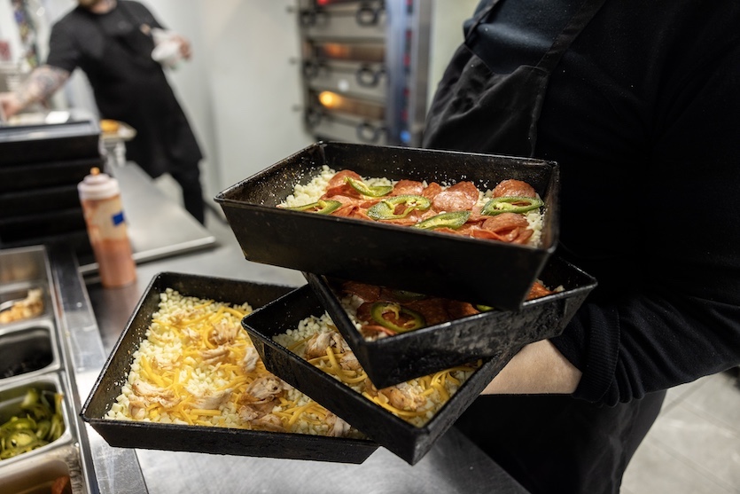 Four Detroit deep-dish pizzas are rushed to the oven at the Michigan & Trumbull pizzeria.