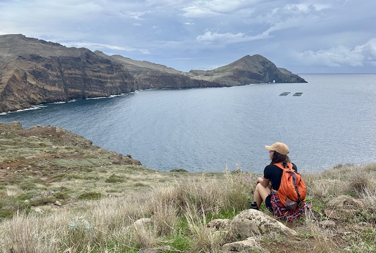 Woman backpacker looks across an ocean cove on Madeira.