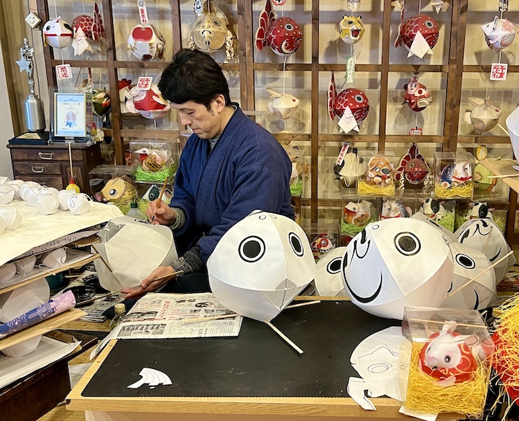 An artisan paints goldfish, revered as a symbol of good luck, at Neputa Village, which offers a variety of craft workshops for visitors.