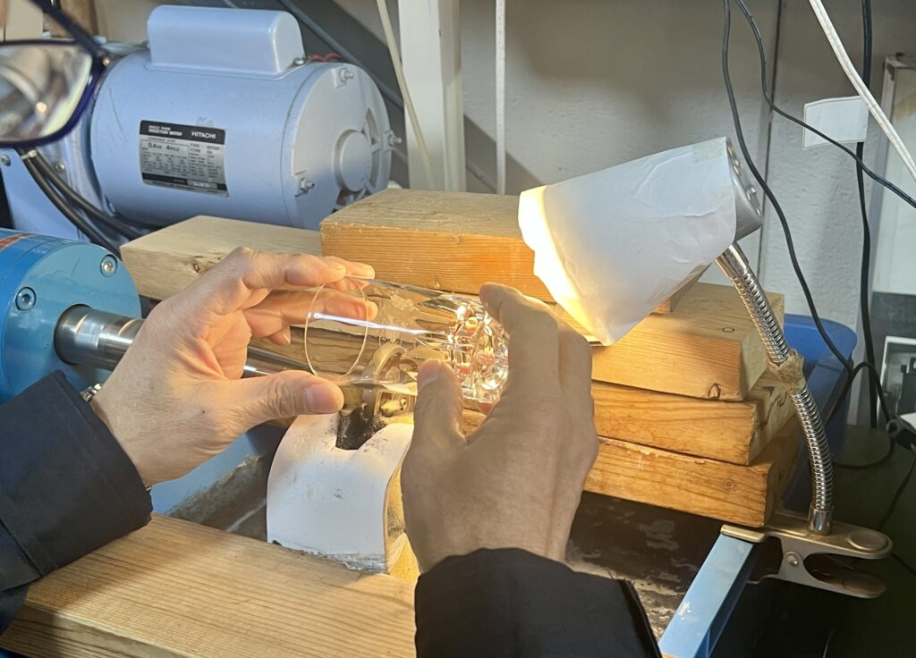 Ojima-san demonstrates glass cutting on clear glass, which he buys in bulk from a manufacturer for his workshops. He procures his colored glass from a company that handmakes them, which he uses for the Edo kiriko he sells in his shop.