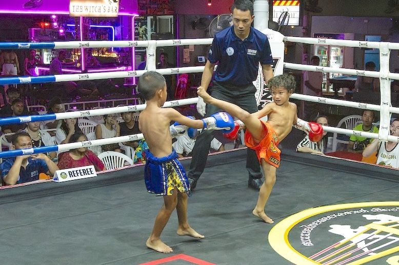 Seven-year-old Goku Alexander, right, unleashes a strong kick in a Muay Thai fight against rival Pod Pingkong. Children start at an early age to learn the traditional Thai martial art. 