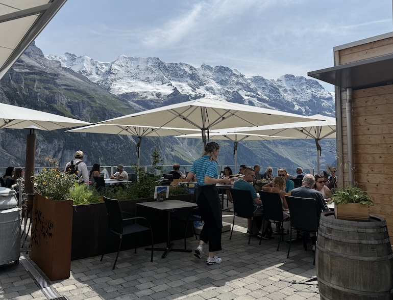 Diners at the Edelweiss Restaurant in car-free Mürren enjoy authentic Swiss dishes on the sun terrace with views of Eiger, Mönch, and Jungfrau. 