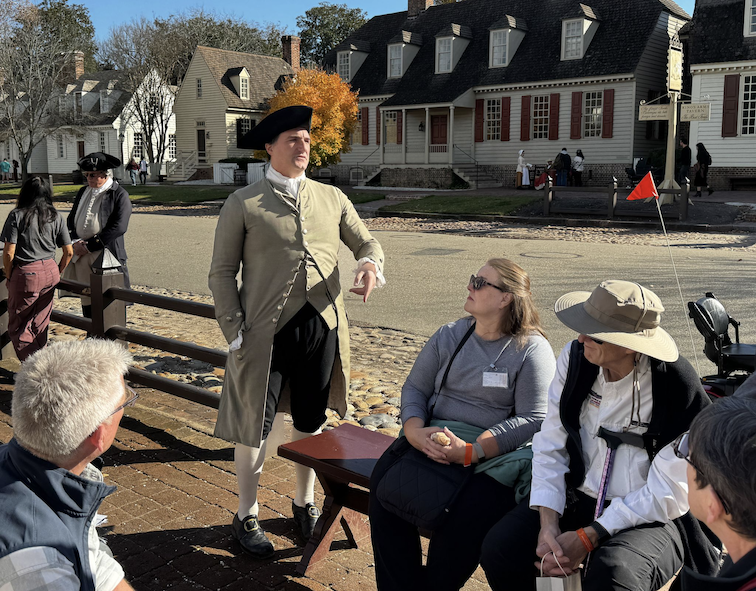 Owner of Raleigh Tavern steps away from the bar to talk with 21st Century visitors who have questions about life in 1776.