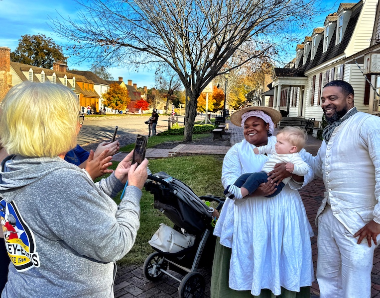 Two African Anerican actors who assume the roles of slaves each day at Williamsburg are asked to pose with family's toddler.