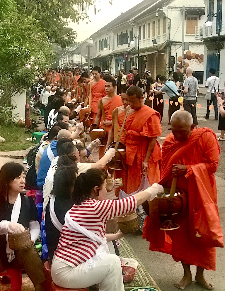 Led by their abbot, barefoot monks accept offerings of rice and other food as they circumambulate the UNESCO world heritage city of Luang Prabang at dawn each day.