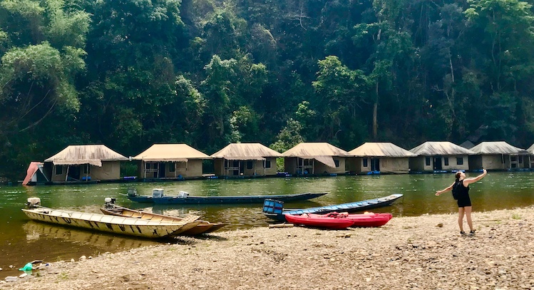 An Australian visitor dances on the shore of a wilderness eco-resort before paddling a kayak down the Nam Khan, a Mekong tributary.