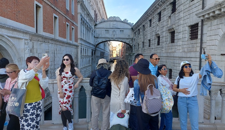 Excited tourists crowd a footbridge for Venice’s iconic view of the Doge’s Palace’s “Bridge of Sighs.”