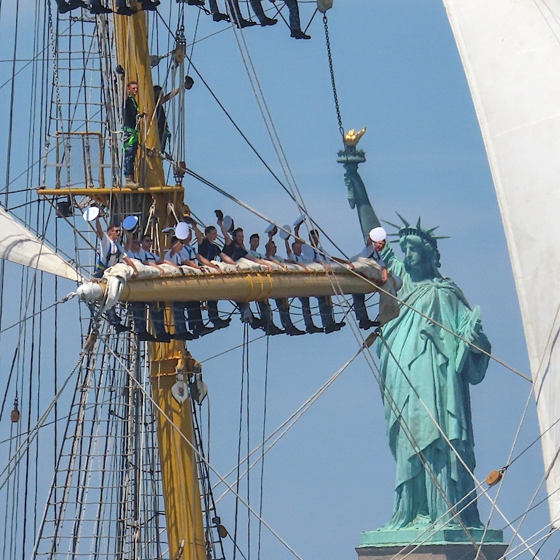 Sailors on Romania’s tall ship, the Mircea, wave to the crowds as they pass the Statue of Liberty.
