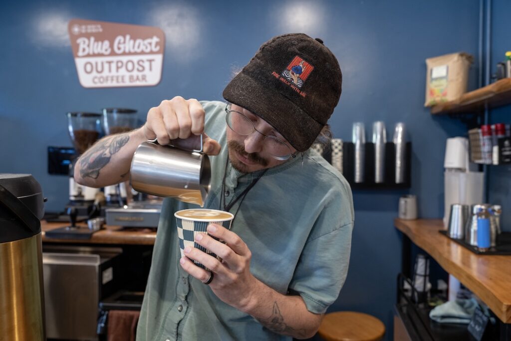 A barista prepares a latte at Blue Ghost Outpost, a coffee bar near the route to Cataloochee Valley.